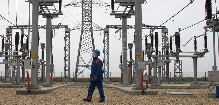 Rețele Electrice employee walking among the equipment in a transformer station